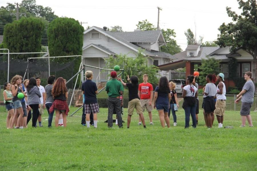 A group of freshmen play a game with a ball in the back field during orientation.